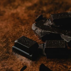 Photo by Eva Bronzini Close-up of dark chocolate pieces on cocoa powder background, showcasing rich texture and color.